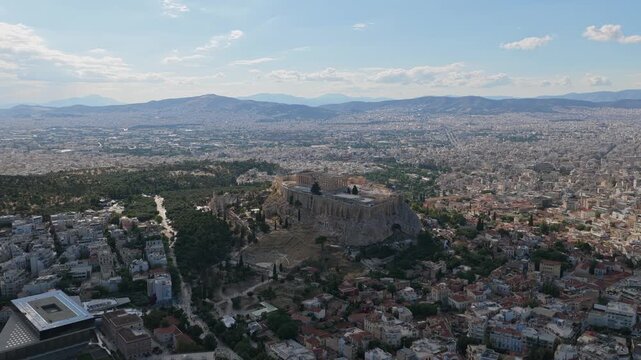 High altitude wide shot of Athens' cityscape revealing ancient Acropolis with Parthenon temple, famous greek historical and archaeological site