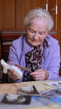 Elderly woman remembering memories looking at old photographs