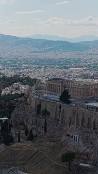 Athens cityscape featuring ancient Acropolis ruins, historic Parthenon temple, Odeon of Herodes Atticus, with distant mountains in vertical