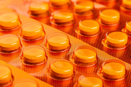 Yellow tablets sealed in orange blister packs in close up view. Healthcare and pharmaceutical concept for medication, treatment, dosage, and packaging.