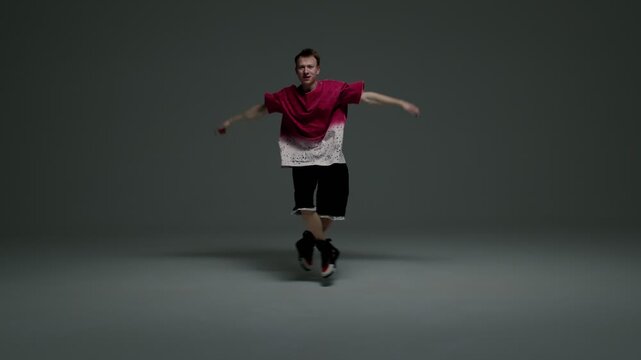 Hip hop dancer jumping with raised arms in minimal studio