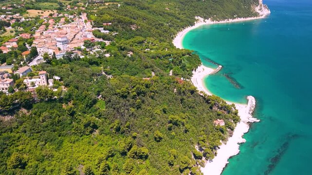 Sirolo Italy 4k drone tilt up from Numana beach to medieval borgo on cliff. Aerial exotic tropical sea panoramic view of Monte Conero mountain coast landscape b-roll