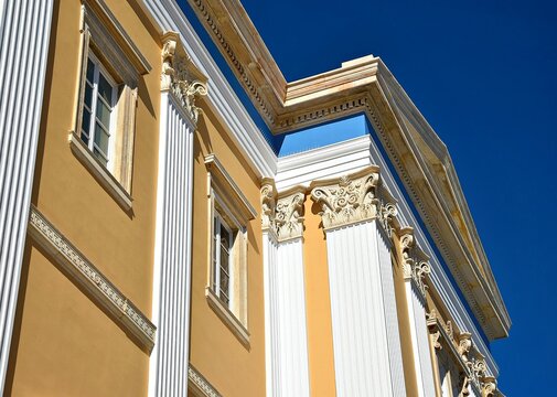 Landscape with scenic exterior view of Aghios Nikolaos, a Byzantine Greek Orthodox church with an ochre stucco wall and marble Ionic columns in Syros island, Cyclades, Greece.