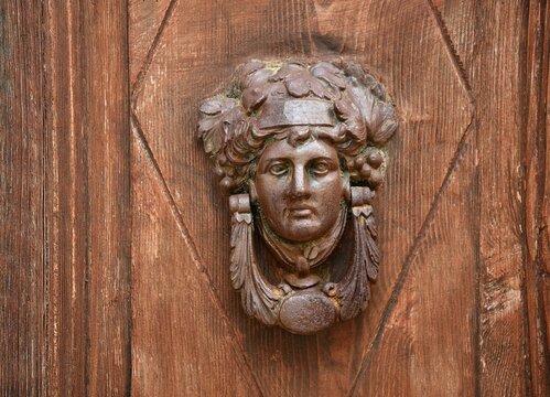 Antique hand carved wooden door with a Greek Goddess head knocker in Koroni, Messinia Peloponnese Greece.