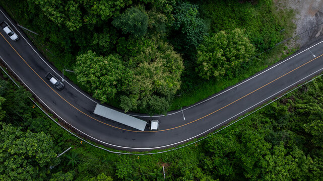 Aerial view EV semi truck trailer cargo on mountain curve road, Semi truck trailer cargo business logistic transportation on green forest road curve, Semi truck delivery asphalt road green forest