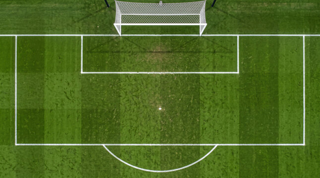 Aerial top down view of empty soccer penalty area with white goal post and field markings on green grass turf