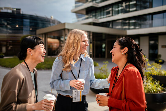 Smiling female professionals networking over coffee outside office
