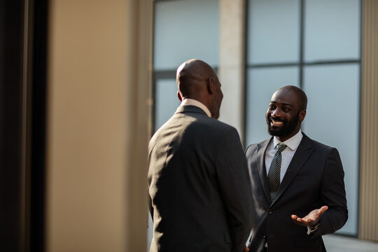 Two businessmen talking in a modern office lobby