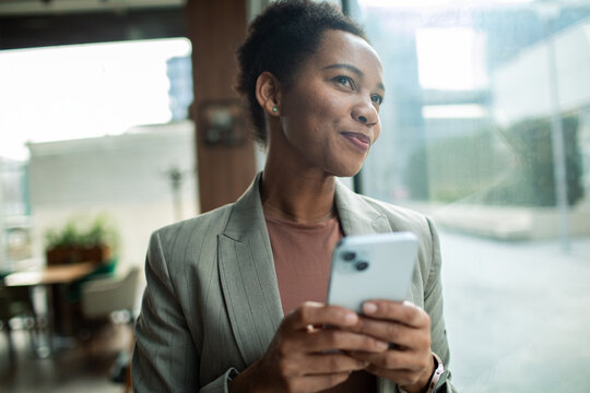 Smiling businesswoman using smartphone by office window