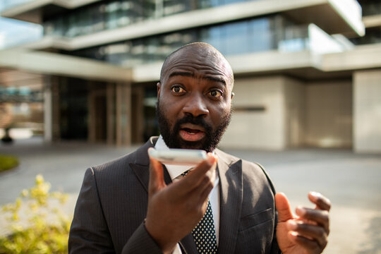 Businessman using voice assistant outside office building