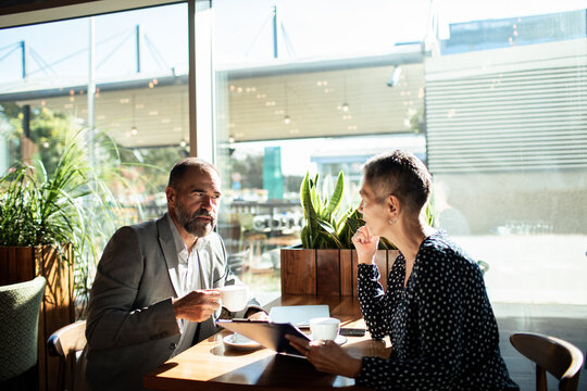 Two business professionals meeting over coffee in a sunlit cafe