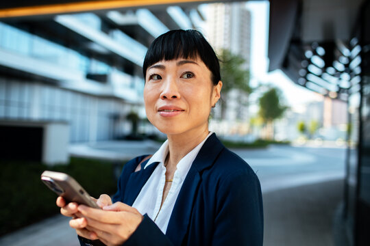 Confident businesswoman using smartphone in modern city