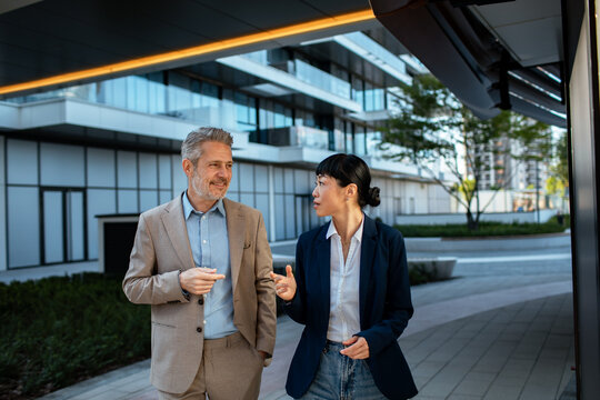 Business colleagues talking while walking outside office complex