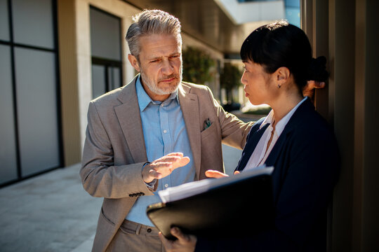 Two business colleagues discussing project outside office building
