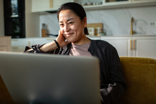Smiling woman using laptop in home kitchen