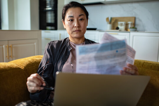 Concerned woman reviewing bills on laptop at home