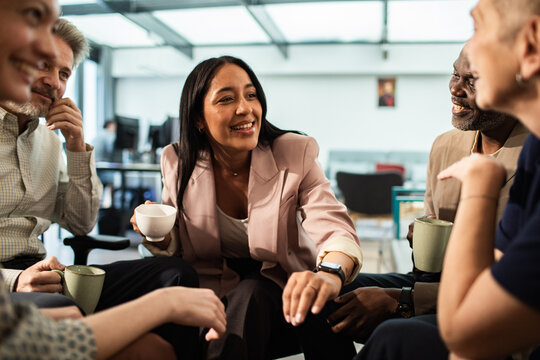 Diverse coworkers chatting during coffee break in modern office