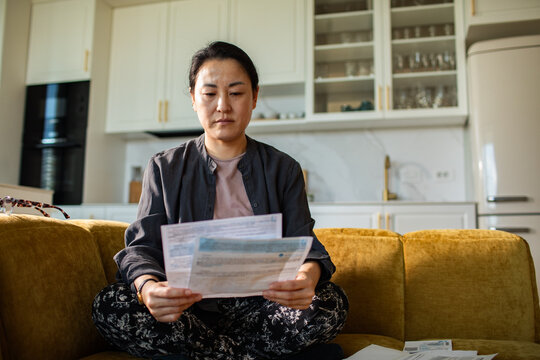 Woman reviewing household bills on sofa at home