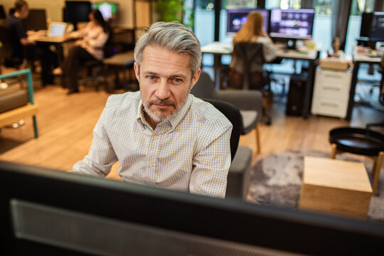 Focused senior man working at computer in modern open-plan office