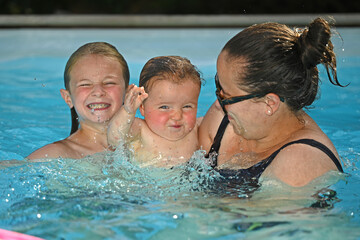 Fototapeta premium Mother teaching her baby the basics of movement in a swimming pool