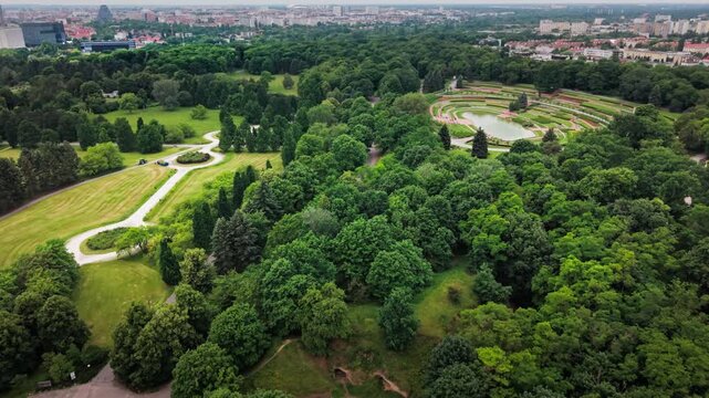 Green Urban Park Meadow People Relaxing Cityscape Skyline Horizon Aerial View Lifestyle Commercial. This elevated drone perspective captures a sunny public park lawn where citizens enjoy leisure time
