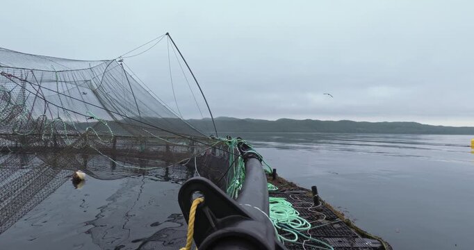 Large fish farm in the water with nets under cloudy sky as background