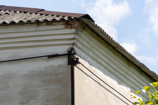 Metal structural tie rod reinforcing the corner of an old masonry house under a slate roof, building maintenance, structural engineering and foundation repair concept