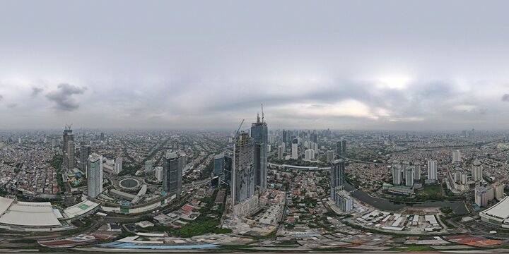 Aerial view of Jakarta Pusat skyline featuring modern skyscrapers under construction, dense urban residential areas, and winding roads in Kecamatan Menteng, Daerah Khusus Ibukota, Indonesia.
