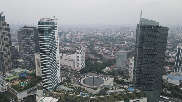 Aerial view of the Bundaran HI roundabout surrounded by modern skyscrapers and urban greenery in the heart of the city, Kecamatan Menteng, Daerah Khusus Ibukota, Indonesia.