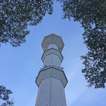 Low-angle view of a tall white mosque minaret against a blue sky