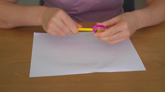 Woman sharpening a colored pencil with a sharpener at a table, high quality audio recording. Soft grinding and shaving sounds. Drawing preparation, craft and everyday lifestyle concept.