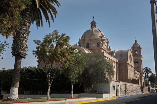 Tacna Cathedral presides over the main plaza in warm rose-tinted stone under an immaculate deep blue sky, its twin baroque bell towers and ornate neoclassical facade creating one of the most architect