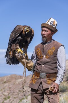 Traditional Kyrgyz eagle hunter with eagle in the mountains, near Kysyl-Suu, Kyrgyzstan