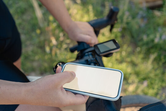 Cyclist holding smartphone navigating on gravel path