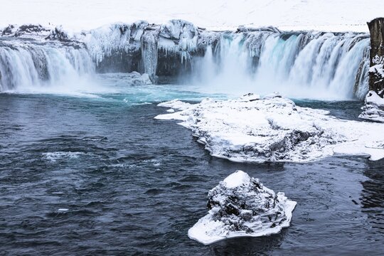 Ice layer in the river Skialfandaljot, behind it the waterfall Godafoss, Northern Iceland Eyestra, Iceland