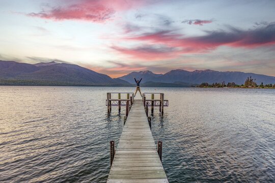 Juger man takes a skydive, jetty at the lake, Lake Te Anau at sunset, Te Anau, South Island, New Zealand