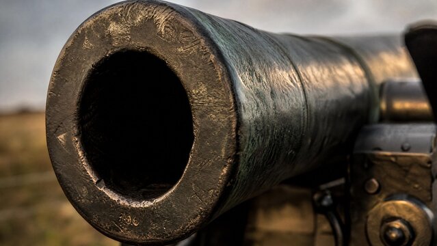 Extreme close-up of the muzzle of an old-fashioned field cannon, highlighting worn metal texture.