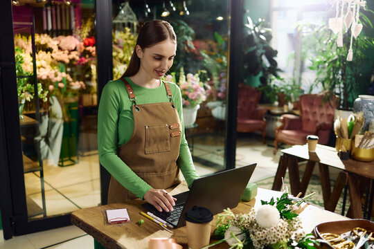 Young adult Caucasian woman florist managing laptop orders in flower shop, supporting small business workflow. Useful for retail marketing, ecommerce, entrepreneurship content