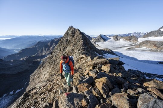 Mountaineer on a rocky ridge, ascent to the Wilder Freiger, summit of the Becher with Becherhaus behind, picturesque high mountain landscape, view of the &Uuml;beltalferner glacier and rocky mountain peaks, Stubai Alps, South Tyrol, Italy