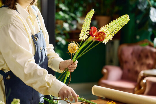Unrecognizable woman arranging flower bouquet at worktable in florist shop, preparing stems for retail display. Ideal for small business, handmade retail, floral service marketing