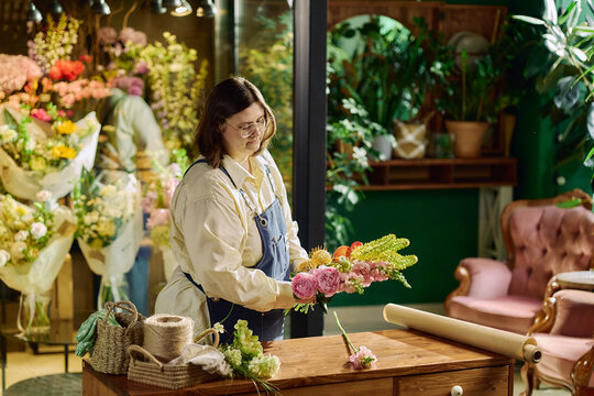 Young adult florist arranging bouquet in flower shop, preparing retail order and showcasing small business craftsmanship. Useful for local commerce, retail branding, entrepreneurship