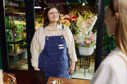 Caucasian florist assisting female customer in flower shop, discussing bouquet order and retail service. Useful for small business, local commerce, customer care marketing