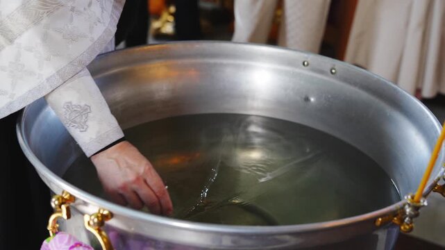Priest prepares water for a baptism ceremony in church