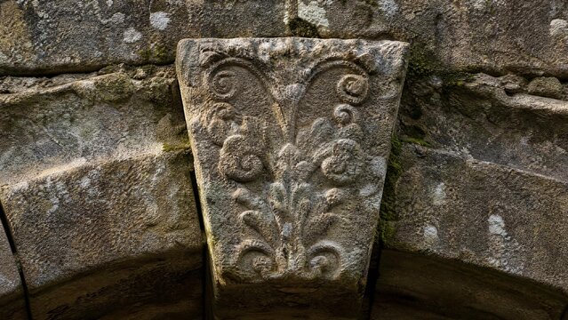 Ancient stone arch bridge keystone with intricate weathered carvings.