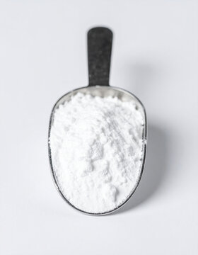 Tiny metallic scoop with pure white titanium dioxide powder. Isolated on sterile white background. Close-up.