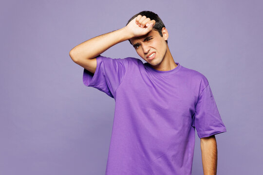 Young sad sick ill tired Caucasian man wear violet t-shirt casual clothes put hand on forehead suffer from headache isolated on plain pastel light purple background studio portrait. Lifestyle concept.