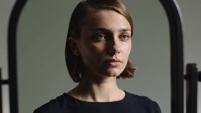 Tilting chin, shifting gaze on camera cue, model wearing boatneck at gray backdrop with oval frame