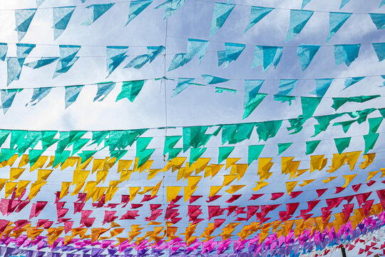 V&aacute;rios varais com bandeirolas coloridas, balan&ccedil;ando ao vento com c&eacute;u ao fundo.
