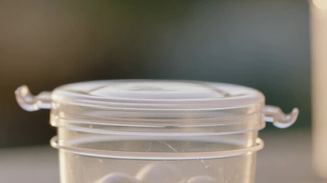 Closing hand pressing down pill box lid at garden table after lifting edge, securing tablets