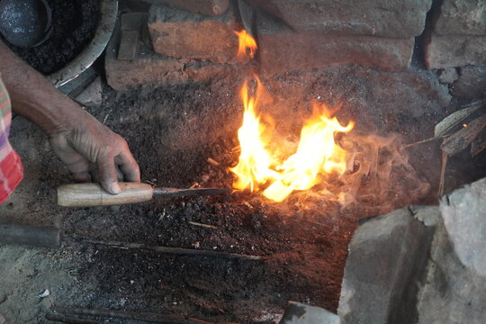 Blacksmith Heating Metal Rod in Forge Fire